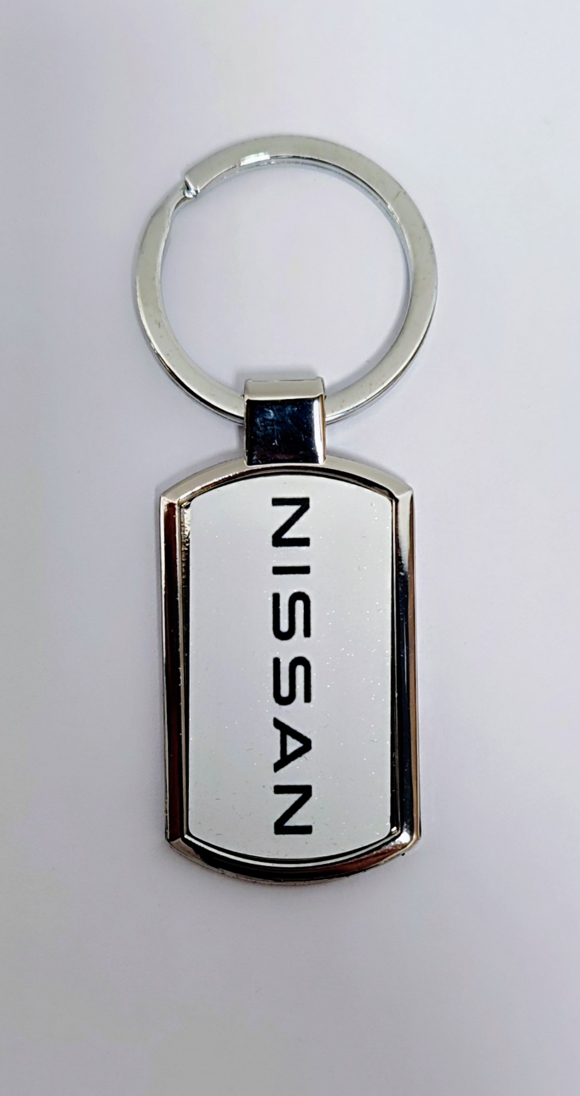 Брелок Nissan, в коробці прямокутний із заокругленими сторонами білий металевий, 38*20 мм (43672)