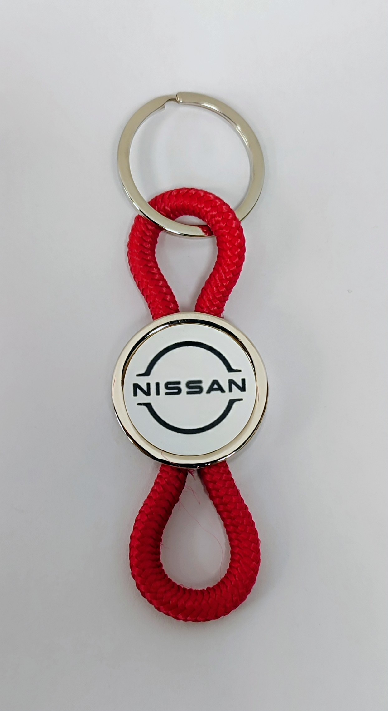 Брелок Nissan, білий круглий металевий з двома червоними петличками, d=26 мм (43676)
